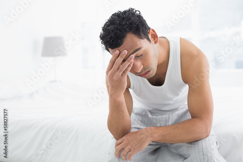 Photo: Man suffering from headache in bed Man suffering from headache in bed