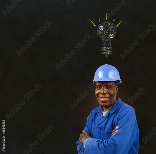Photo: Black man worker with a chalk gear lightbulb on a blackboard Black man worker with a chalk gear lightbulb on a blackboard
