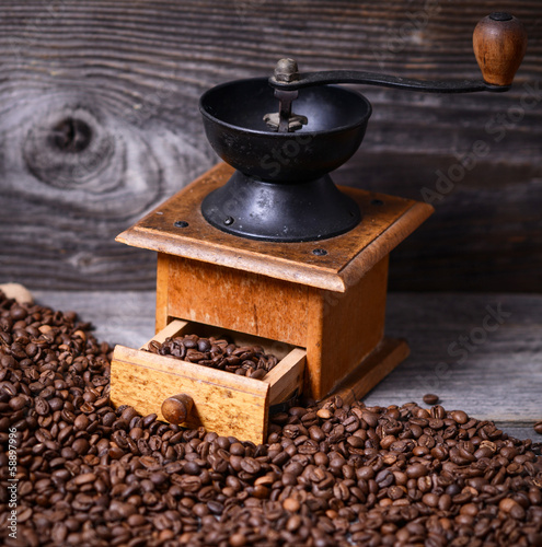 Photo: Manual coffee grinder with beans on wooden background Manual coffee grinder with beans on wooden background