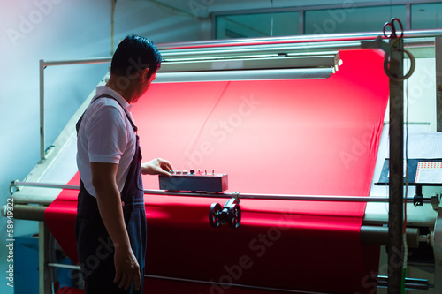 Photo: Asian worker controls fabrics in textile plant Asian worker controls fabrics in textile plant