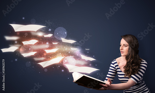 Photo: Young lady reading a book with flying sheets coming out of the b Young lady reading a book with flying sheets coming out of the b
