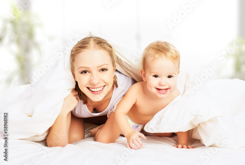 Photo: happy family mother and baby under blankets in bed happy family mother and baby under blankets in bed