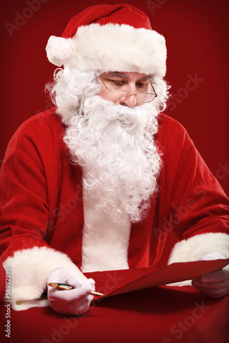 Photo: Portrait of Santa Claus looking at envelope in his hands Portrait of Santa Claus looking at envelope in his hands