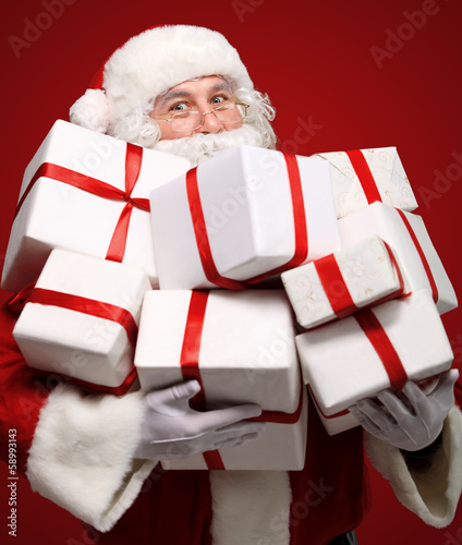 Photo: Photo of Santa Claus with giftboxes looking at camera Photo of Santa Claus with giftboxes looking at camera