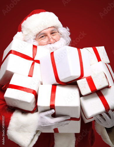 Photo: Photo of Santa Claus with giftboxes looking at camera Photo of Santa Claus with giftboxes looking at camera