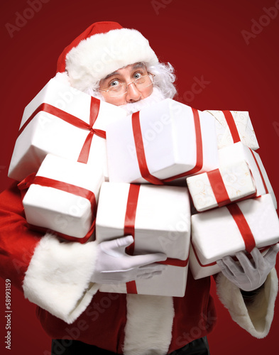 Photo: Photo of Santa Claus with giftboxes looking at camera Photo of Santa Claus with giftboxes looking at camera