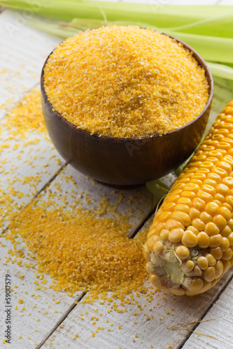 Photo: Corn cob and corn meal on wooden background Corn cob and corn meal on wooden background