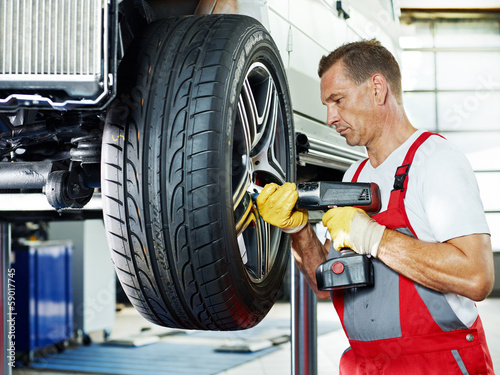 Photo: Motor mechanic is changing a tyre with new alu rim Motor mechanic is changing a tyre with new alu rim