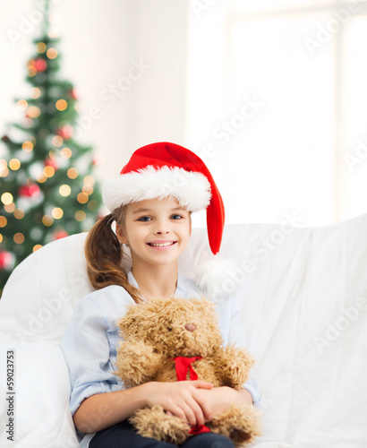 Photo: smiling girl in santa helper hat with teddy bear smiling girl in santa helper hat with teddy bear