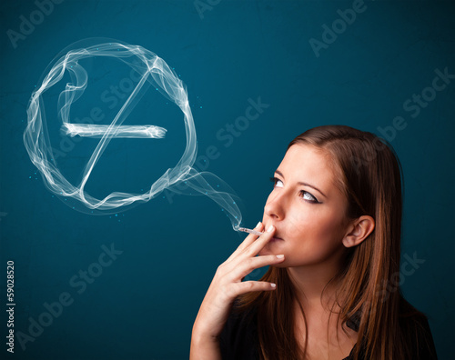 Photo: Young lady smoking unhealthy cigarette with no smoking sign Young lady smoking unhealthy cigarette with no smoking sign