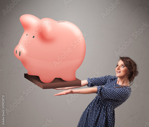 Photo: Young girl holding a huge savings piggy bank Young girl holding a huge savings piggy bank