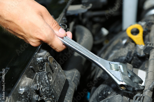 Photo: Hand with wrench. Auto mechanic in car repair Hand with wrench. Auto mechanic in car repair
