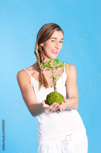 Photo: Young Woman holding a small tree Young Woman holding a small tree