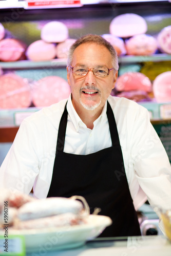 Photo: Shopkeeper showing a bologna in an italian grocery store Shopkeeper showing a bologna in an italian grocery store