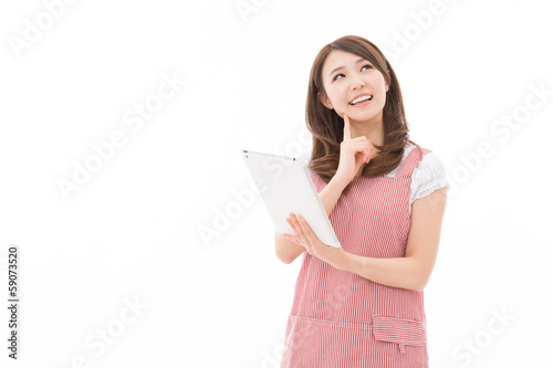 Photo: タブレットを見ながら料理をする女性 タブレットを見ながら料理をする女性