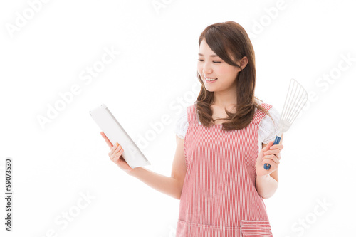 Photo: タブレットを見ながら料理をする女性 タブレットを見ながら料理をする女性