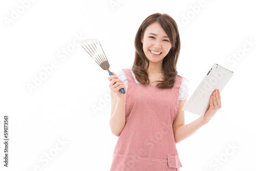 Photo: タブレットを見ながら料理をする女性 タブレットを見ながら料理をする女性