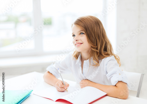 Photo: student girl writing in notebook at school student girl writing in notebook at school