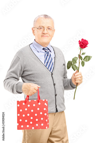 Photo: Mature gentleman holding a rose flower and bag Mature gentleman holding a rose flower and bag