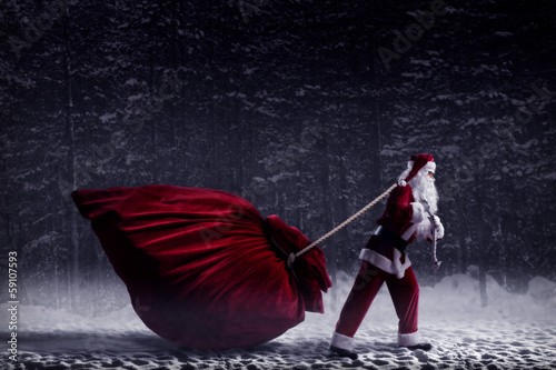 Photo: Santa Claus pulls a huge bag of gifts Santa Claus pulls a huge bag of gifts
