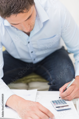 Photo: Close-up of a young man with bills and calculator Close-up of a young man with bills and calculator