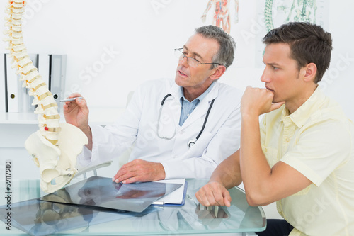 Photo: Doctor explaining spine to a patient in office Doctor explaining spine to a patient in office