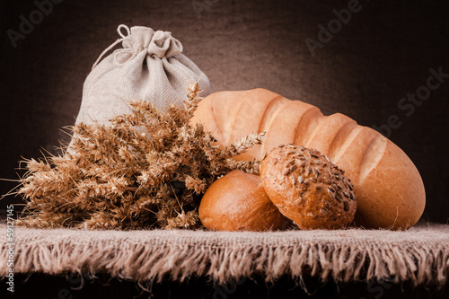 Photo: Bread, flour sack and ears bunch still life Bread, flour sack and ears bunch still life