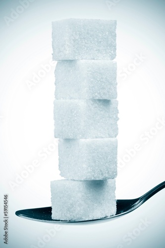 Photo: stack of sugar cubes in spoon. isolated on white stack of sugar cubes in spoon. isolated on white