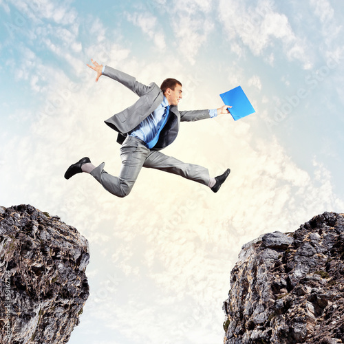 Photo: Businessman jumping over gap Businessman jumping over gap