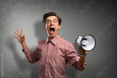 Photo: Portrait of a young man shouting using megaphone Portrait of a young man shouting using megaphone