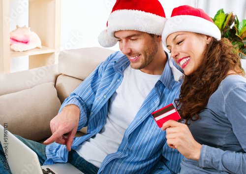 Photo: Christmas E-Shopping. Couple Using Credit Card to Internet Shop Christmas E-Shopping. Couple Using Credit Card to Internet Shop