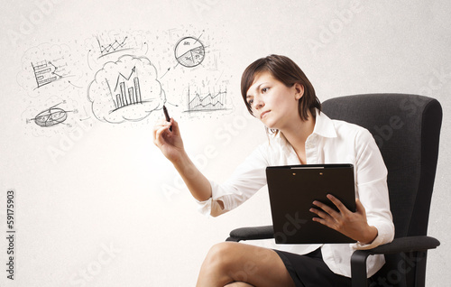 Photo: Young lady sketching financial chart icons and symbols Young lady sketching financial chart icons and symbols