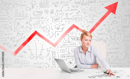 Photo: Business woman sitting at table with market diagrams Business woman sitting at table with market diagrams