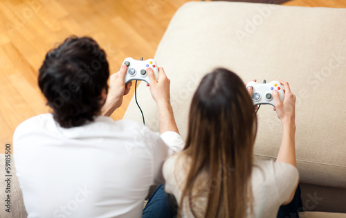 Photo: Young couple playing video games at home Young couple playing video games at home