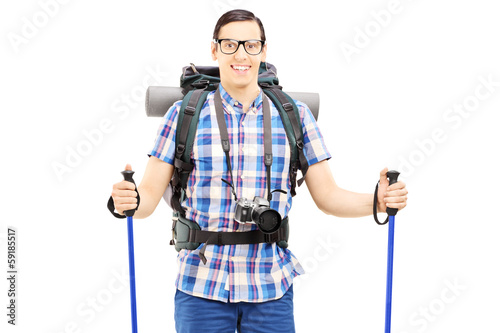 Photo: Smiling hiker with backpack and hiking poles posing Smiling hiker with backpack and hiking poles posing