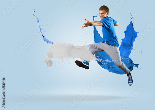 Photo: young male dancer jumping with splash of paint young male dancer jumping with splash of paint