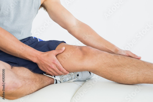Photo: Man with his hands on a painful leg Man with his hands on a painful leg