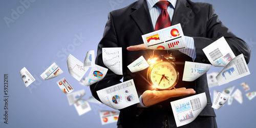 Photo: Business man holding alarmclock Business man holding alarmclock