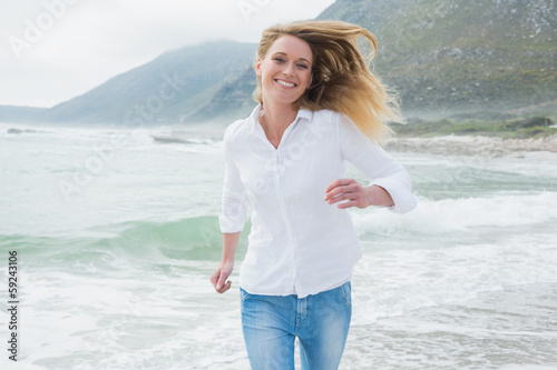 Photo: Portrait of a smiling woman running at beach Portrait of a smiling woman running at beach