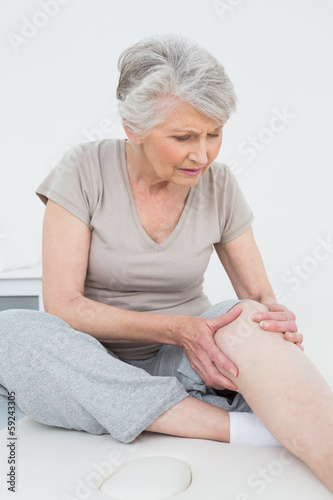 Photo: Senior woman with her hands on a painful knee Senior woman with her hands on a painful knee