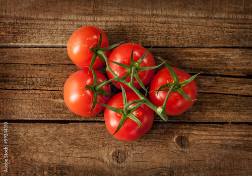 Photo: Fresh wet tomato branch on vintage wood table Fresh wet tomato branch on vintage wood table