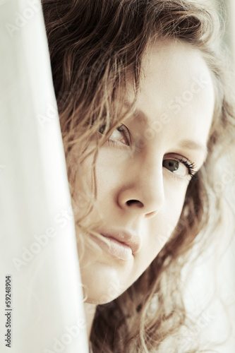 Photo: Sad beautiful woman looking out window Sad beautiful woman looking out window