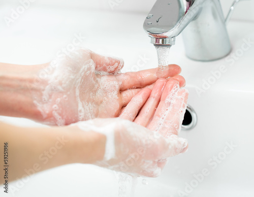 Photo: Washing of female hands with soap in bathroom close up Washing of female hands with soap in bathroom close up
