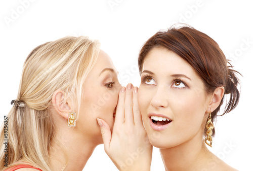 Photo: two smiling women whispering gossip two smiling women whispering gossip