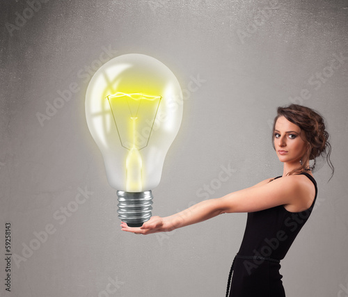 Photo: Beautiful lady holding realistic 3d light bulb Beautiful lady holding realistic 3d light bulb