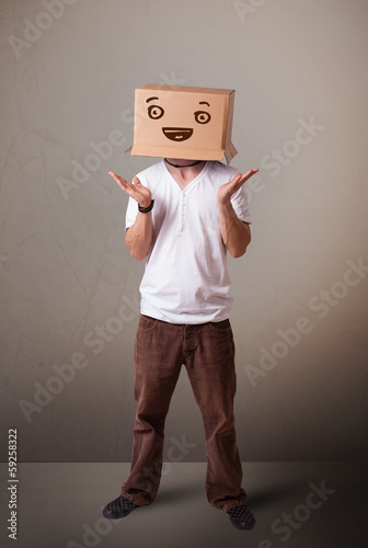 Photo: Young man gesturing with a cardboard box on his head with smiley Young man gesturing with a cardboard box on his head with smiley