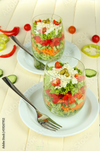 Photo: Tasty salad with fresh vegetables on wooden table Tasty salad with fresh vegetables on wooden table