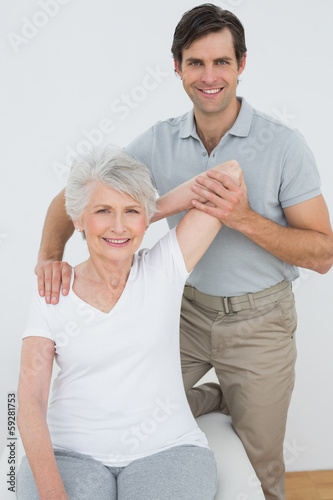 Photo: Physiotherapist stretching a smiling senior woman's arm Physiotherapist stretching a smiling senior woman's arm