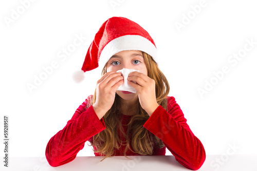 Photo: Christmas Santa kid girl blowing her nose in a winter cold Christmas Santa kid girl blowing her nose in a winter cold