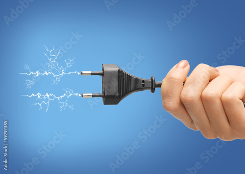 Photo: hand holding black electrical plug with wire hand holding black electrical plug with wire